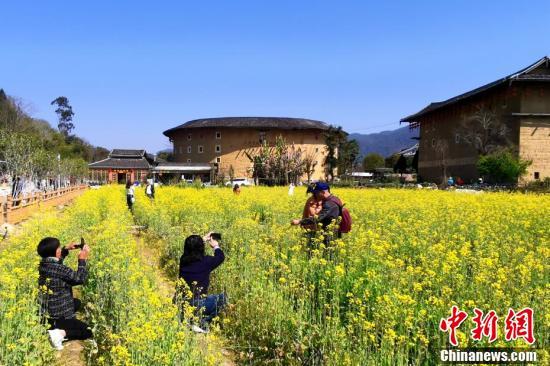 游客在南靖土楼前赏油菜花拍照。张金川 摄